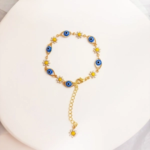 Detail von 14K vergoldetem Armband mit Evil-Eye-Anhängern und Gänseblümchen-Anhängern
