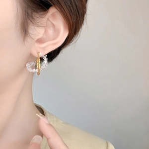 Close-up of geometric gold earrings with cubic zirconia heart-shaped crystal on model