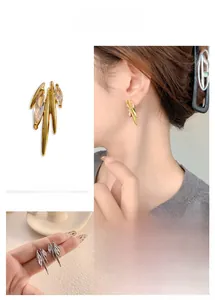 Macro detail of avant-garde irregular stud earrings with marquise-cut zircon in gold and silver