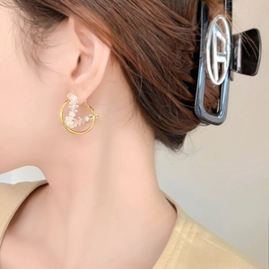 Elegant gold hoop earrings with zircon crystals shown on model in a soft warm profile view
