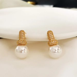 Elegant 18K gold plated zircon and white pearl stud earrings on ceramic tray