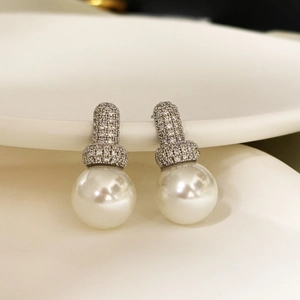 Macro shot of elegant pearl stud earrings with micro-set cubic zirconia in 18K gold finish