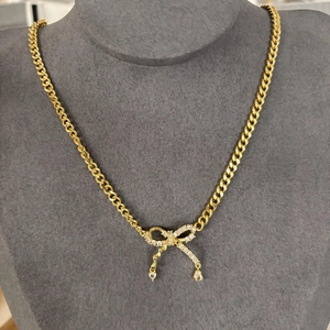 Collier chaîne cubaine dorée avec pendentif nœud en zircon et breloques gouttes sur buste