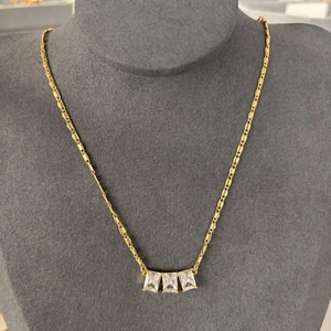 Collier doré avec trois pendentifs en zircone rectangulaire sur un buste de mannequin gris