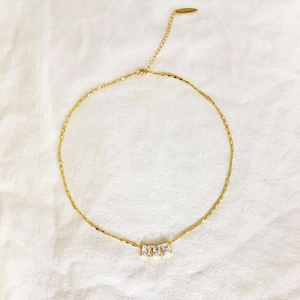 Collier élégant en cuivre plaqué or avec trois zircons rectangulaires sur fond en lin blanc