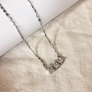 Vue macro du collier argenté avec trois pierres de zircon rectangulaires sur chaîne fine
