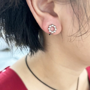 Mini cerchi a fiore in argento con texture a perline indossati sul lobo dell'orecchio