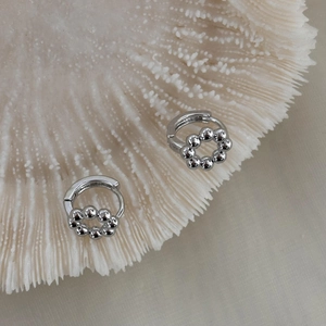 Vista macro di orecchini a cerchio in argento con dettagli di perle lucide a cerchio