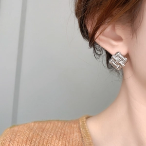 Close-up of geometric square woven earrings in silver plating worn on earlobe