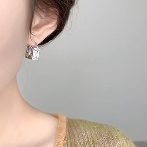 Close-up of geometric rectangular silver earrings with cubic zirconia worn by model
