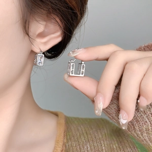Close-up of square sugar-cube zircon earrings with gold plating on a model ear