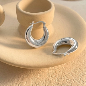 Close-up of chunky silver waterdrop hoop earrings with polished mirror finish