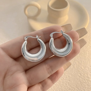 Macro view of chunky silver hoop earrings with polished finish held in a hand