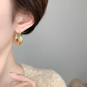 Close-up of chunky gold geometric C-shaped earrings on a model for a modern look