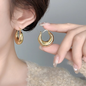 Close-up of chunky geometric round hollow earrings with high-polish 18K gold finish