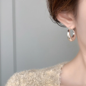 Close-up of chunky silver hoop earrings on model with cozy white knitted sweater