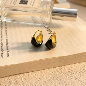 Détail de boucles d'oreilles en or en U avec émail noir sur fond de livre