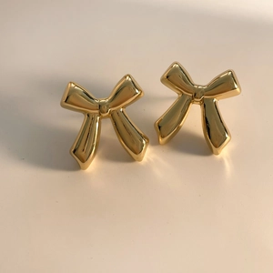 Detail view of 3D golden bow earrings with a polished metallic mirror finish