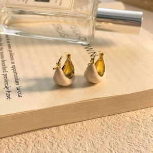 Gros plan de boucles d'oreilles en émail crème en forme de U sur une page de livre