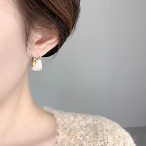 Gros plan de boucles d'oreilles dorées en U avec émail blanc crème sur le mannequin