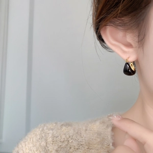 Détail des boucles d'oreilles en émail noir en forme de U avec placage or 18 carats sur modèle