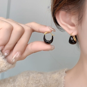 Gros plan de boucles d'oreilles en U émaillées noires plaquées or 18 carats sur modèle