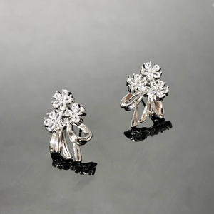 Detailed macro view of zircon flower and bow stud earrings with polished silver finish
