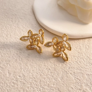 Gros plan de boucles d'oreilles fleurs dorées avec cristaux et perles blanches
