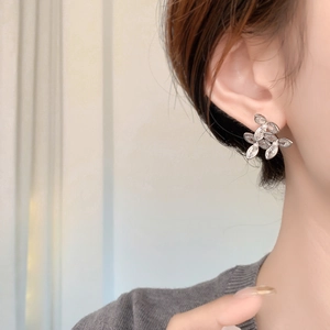 Gros plan de boucles d'oreilles fleur en argent avec zircons et petites perles sur l'oreille