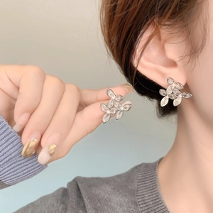 Gros plan d'une boucle d'oreille fleur en zircon et perle portée par un mannequin