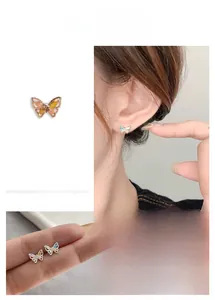 Detailed view of mini butterfly stud earrings with colorful zircon stones on model ear