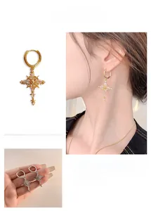 Detail of gold cross star earrings with zircon inlay and elegant dangling fringe drop