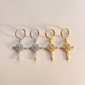 Luxurious cross earrings with zircon stones in gold and silver plating on white surface
