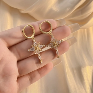 Luxury gold-plated cross earrings with sparkling zircon stones shown on champagne silk