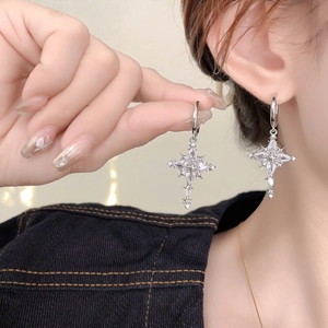 Detailed view of silver cross star earrings with sparkling cubic zirconia on a model