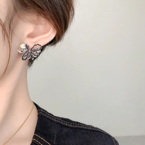 Nahaufnahme eleganter Schmetterlings-Ohrstecker mit Kristallen an einem Model