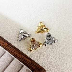Geometric zircon stud earrings in gold and silver plating shown on a white textured background