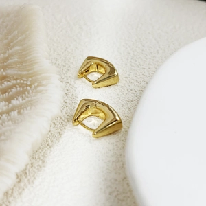 Macro shot of 18K gold-plated geometric triangle earrings on elegant white coral