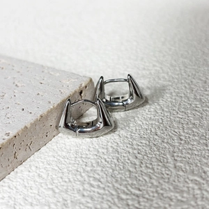 Detailed view of wide arched geometric earrings in polished silver finish on stone base