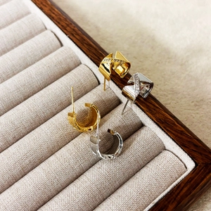 Détail de boucles d'oreilles en C dorées et argentées avec zircons sur un support à bijoux
