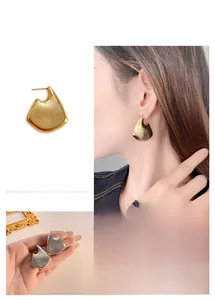 Detailed view of hollow geometric earrings with brushed gold and silver metal textures