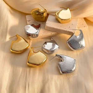 Detailed display of irregular geometric gold and silver earrings on silk and marble