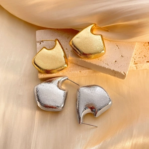 Modern hollow geometric earrings in gold and silver finish on elegant silk background