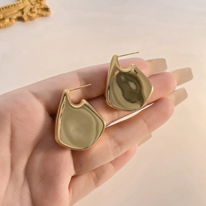 Detailed close-up of gold-plated geometric drop earrings with a polished mirror finish