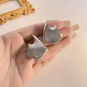 Detailed view of silver C-shaped hoop earrings with handcrafted hammered metal texture