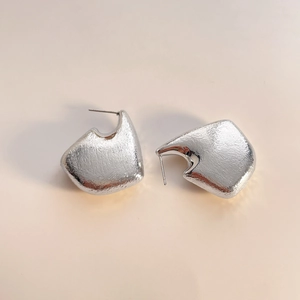 Detail of silver irregular hollow earrings with a textured matte brushed finish