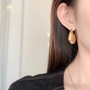 Detail of high-quality gold plated water drop earrings with hammered texture on ear