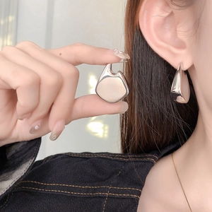 Close-up of silver hollow geometric earrings with high-polish finish on ears