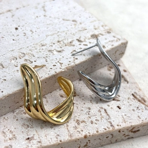 Polished 18K gold and silver plated wavy ribbon stud earrings on stone tray