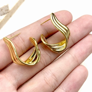 Macro view of gold ribbon earrings with a polished surface in a unique wavy ribbon design